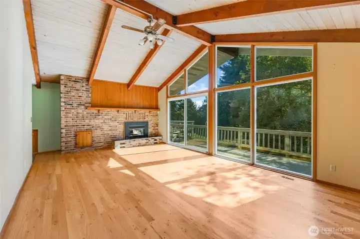 Main living room has original beams, white washed wood ceiling that extends to back deck. Updated windows, brick surround with gas fireplace & beautiful oak hardwood floors