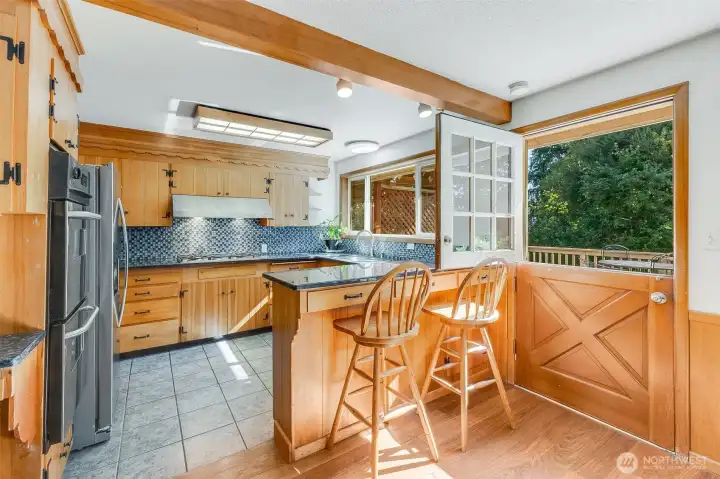 Kitchen has bar seating for 2 and granite countertops, tiled backsplash and original cabinets. The Dutch door is charming that leads to back patio