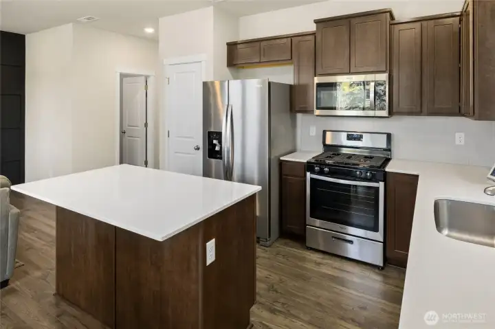 Solid quartz countertops, full-height tile backsplash, stainless undermount sink, stainless steel appliances, mircro hood and gas cooktop.