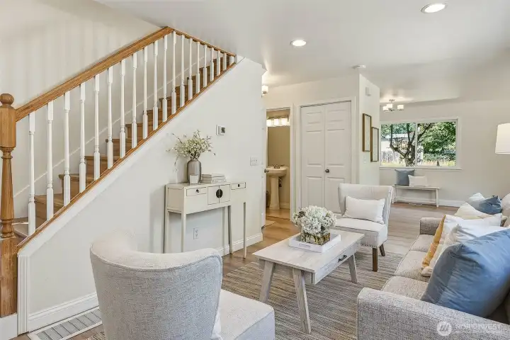 Living room with stairs to bedrooms, powder room, and laundry closet to the right of the powder room