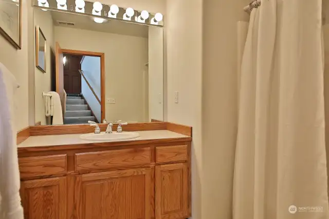 Lower level Full Bath is located at the base of the stairs across from the Laundry Room. You can see the stairs to the entry way in the mirror.