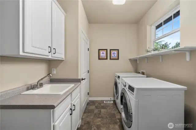 Laundry room includes ample storage and a convenient utility sink