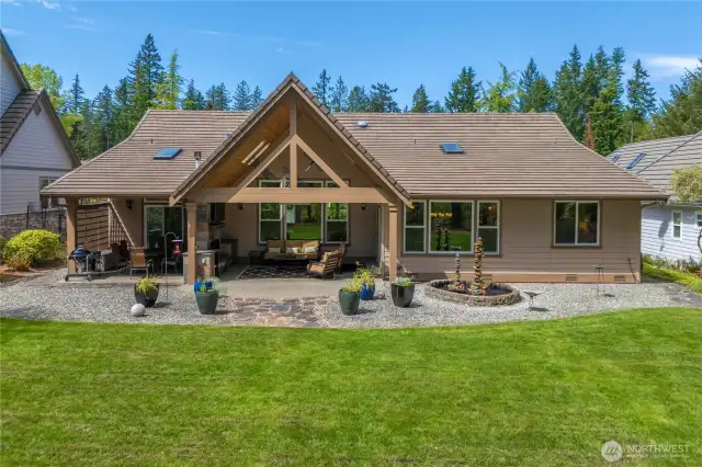 True backyard oasis, ideal for gatherings and relaxation with a spacious patio, built-in fireplace,  TV, heater, and counterspace for outdoor entertainment