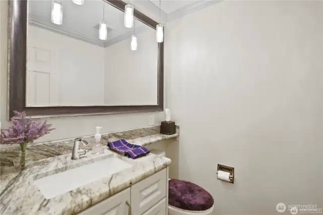 This stylish half bathroom offers functionality with a sleek, modern design. A contemporary vanity with ample counter space is complemented by elegant fixtures and refined lighting.
