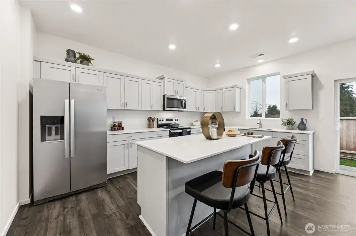 Large kitchen island with quartz counters and breakfast bar all standard. Actual home is under construction and colors, materials, and finishes may vary. See site agent for details.