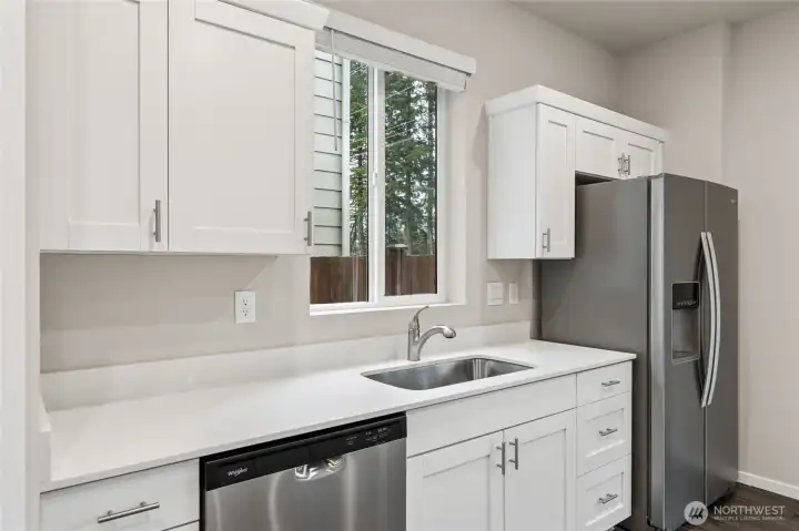 Modern kitchen featuring quartz countertops, stainless steel appliances, and ample cabinetry.