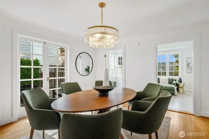 Oversized dining room filled with southern light, featuring French doors to the private side patio and double doors leading to the bright sunroom.