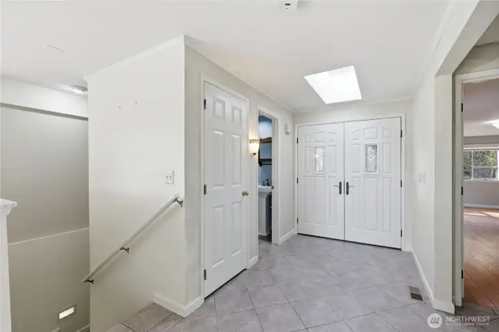 We've walked back through the great room to the foyer. Stairs down to the lower level on the left, both bedrooms on the right, a coat closet and a half bath by the entry.