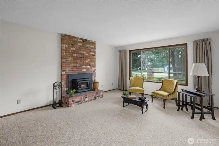 Spacious living room with cozy wood burning stove and large window overlooking the front yard.
