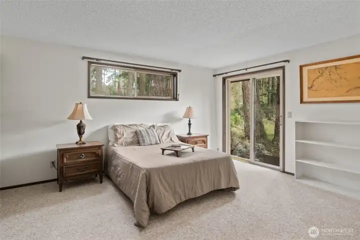 Primary bedroom with sliding glass door to small patio and backyard.