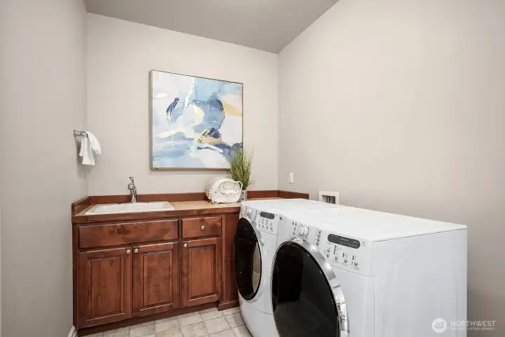 The conveniently located laundry room is both practical and polished, featuring a full-size washer and dryer, rich cabinetry for ample storage, and a clean, well-appointed layout that makes everyday chores a breeze. This thoughtfully designed space adds an extra layer of functionality and convenience to the home's already exceptional floor plan.