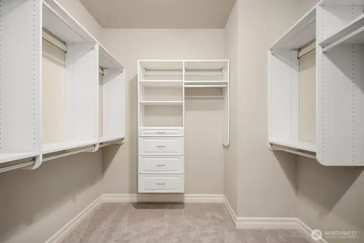 One of two generous walk-in closets in the primary suite, this beautifully appointed space features floor-to-ceiling custom shelving, hanging rods, and dedicated drawer space designed to accommodate an extensive wardrobe with ease. The bright, well-organized layout ensures that every inch of storage is maximized, adding a true luxury touch to this already exceptional primary retreat.
