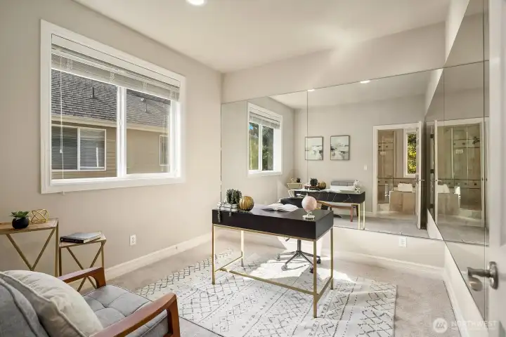 This bright and welcoming bedroom offers the perfect private retreat for guests or multigenerational living, featuring large windows, a dedicated workspace, and a light-filled, airy atmosphere that feels both comfortable and refined. The direct access to a private ensuite bath adds an exceptional level of privacy and convenience for occupants of this thoughtfully designed room.