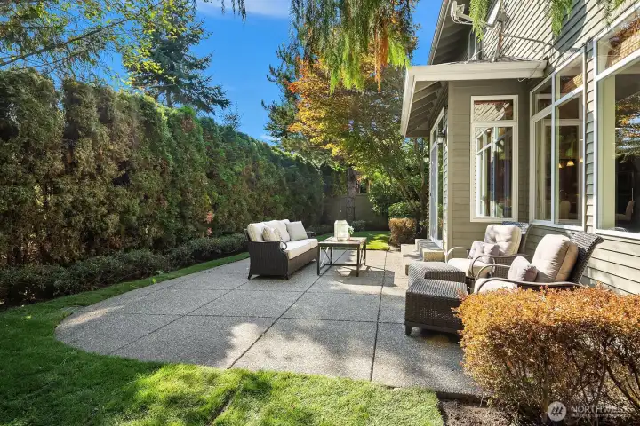 This stunning alternate view of the private backyard showcases the expansive patio space and the incredible wall of mature greenery that creates an exceptional sense of seclusion and serenity. The generous outdoor living area, framed by the home's beautiful craftsman architecture, offers endless possibilities for outdoor entertaining and everyday enjoyment in a truly private setting.