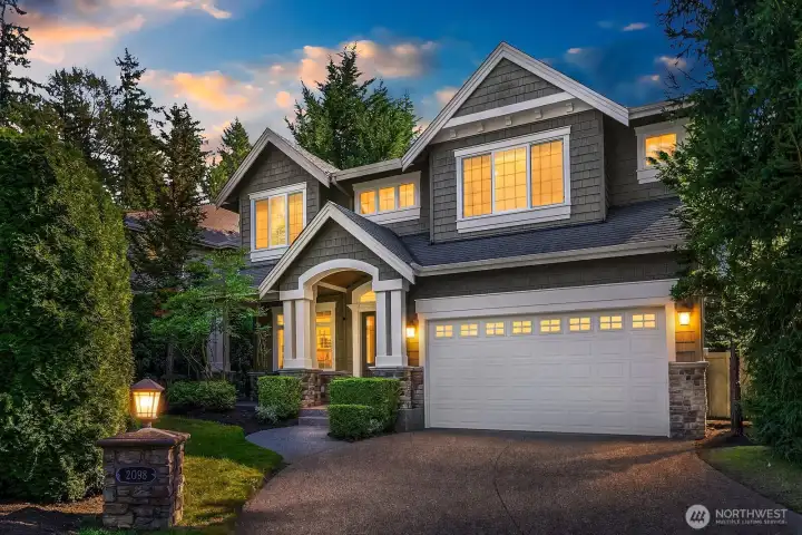 This breathtaking twilight view of the home's exterior showcases the stunning craftsman architecture at its most dramatic, with warm interior lighting glowing through the windows and professional landscape lighting illuminating the beautiful stone accents and manicured grounds. The combination of the rich exterior finishes, lush landscaping, and evening ambiance creates an absolutely captivating first impression that is sure to stop buyers in their tracks.