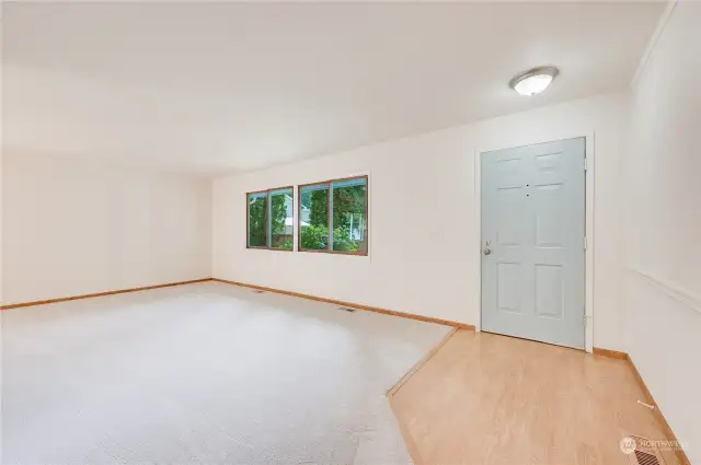 Front door entry to spacious living room with new carpeting and paint