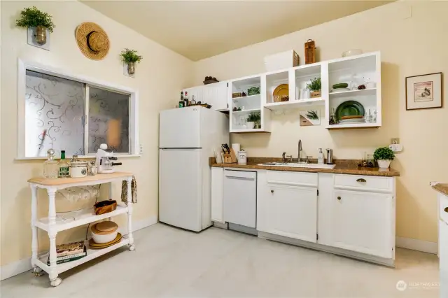 This adorable kitchen features easy-to-maintain luxury vinyl flooring, white millwork, and this charming pass-through window.