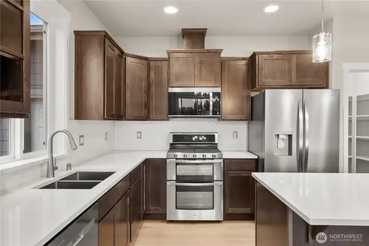 Beautiful graphite-stained maple cabinets, quartz counters and full backsplash make this kitchen a stunner! Gas range/double oven is standard! This home also includes a refrigerator.