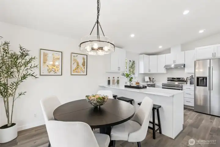 Open dining area seamlessly connected to the kitchen, showcasing modern finishes, stainless steel appliances, and a functional breakfast bar.