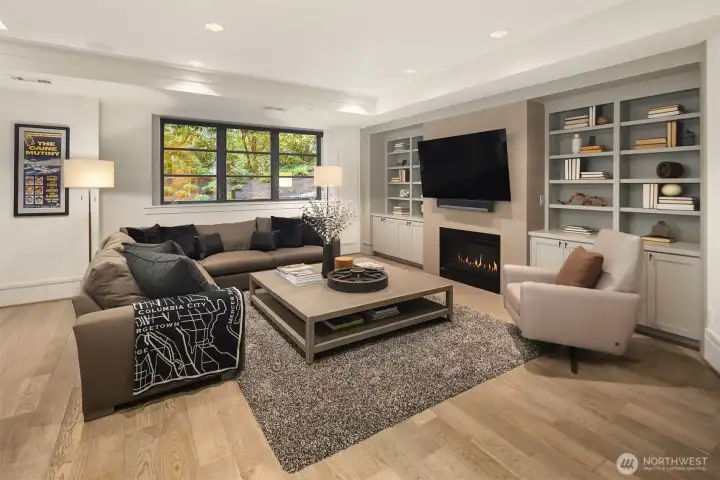 Custom built-in library/media cabinets flank the gas fireplace in the rec room.
