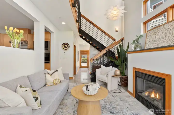 Open-concept main floor with views through to the entry, kitchen, and the sculptural open-tread staircase — the layout lives larger than it looks on paper.