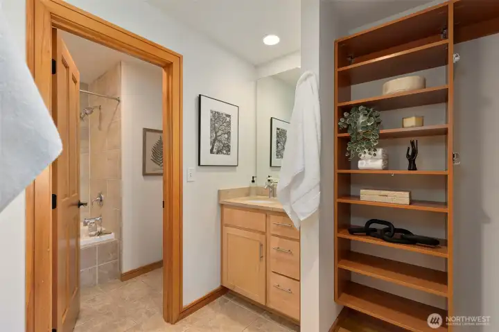 The California Closets walk-through system connects the primary bath to the bedroom — dual vanities with marble countertops flank the passage with generous shelving throughout.