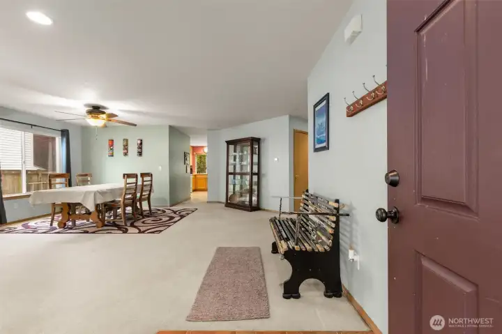 Enter into a large, open living/dining room. Ahead, a hallway leads to the kitchen. Ahead and to the right, another hallway leads to the stairway, garage, powder room, and family room. The closed door opens to a storage closet.