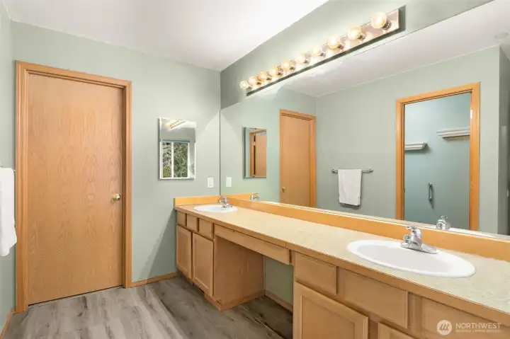 Primary bathroom with dual sinks and a vanity area.
