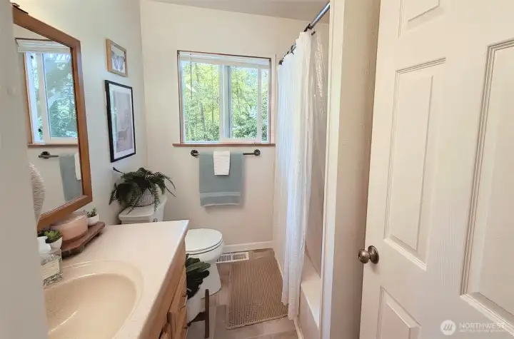 Full main level bathroom, updated vinyl flooring, and shower/tub insert