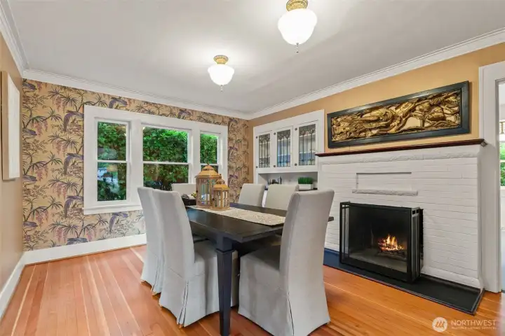 Imagine dinner parties by firelight — this gracious dining room with a working fireplace, leaded glass built-in buffet, and whimsical botanical wallpaper was made for memorable evenings.