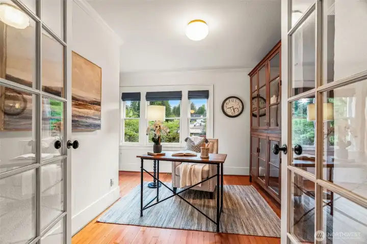 Slip behind the glass-paned French doors and settle into your own quiet retreat — a sun-filled library with original wood floors and garden views on three sides that make working from home feel like a privilege.