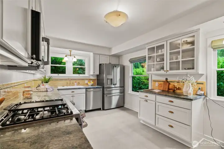 Cook in style in this thoughtfully updated kitchen, where brand-new stainless appliances, rich granite countertops, and warm golden subway tile backsplash bring fresh energy to classic bones — a garden window above the sink keeps you connected to the lush surroundings while you cook.