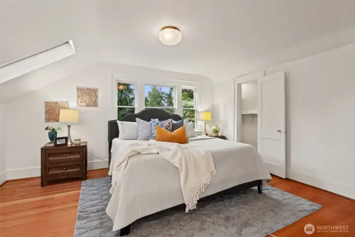 This serene primary bedroom with original wood floors, vaulted ceiling, and generous closet space offers a peaceful retreat at the end of every day.