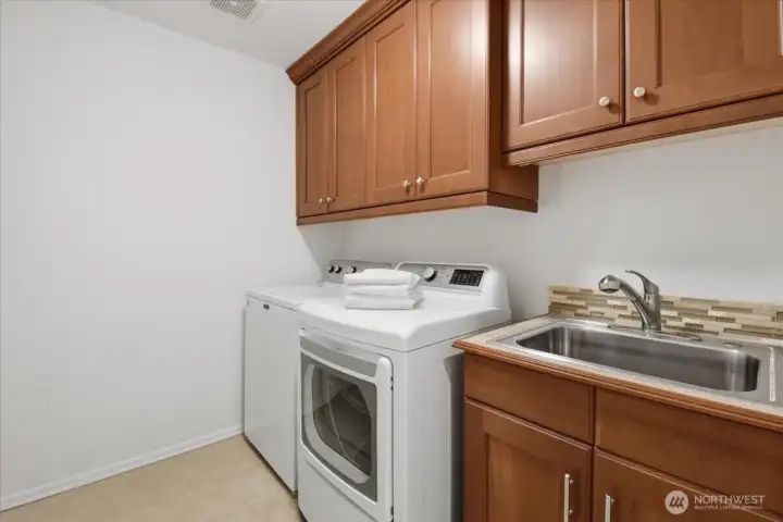 The laundry has cabinets and a soaking sink. The laundry has cabinets and a soaking sink.