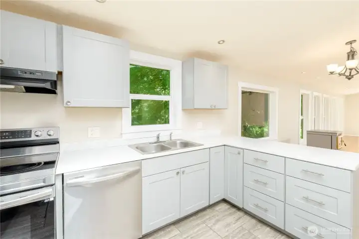 Bright, updated kitchen with generous cabinet space, quartz-style counters, skylight, and an open layout overlooking the dining area.