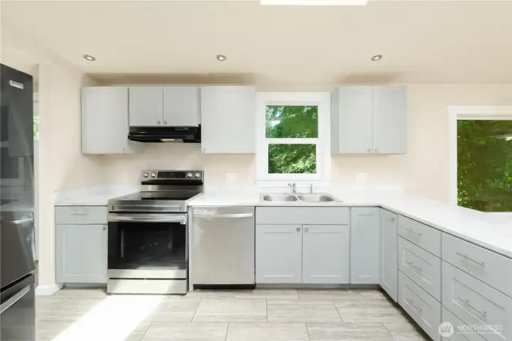 Updated kitchen features ample cabinetry, stainless steel appliances, generous counter space, and a window overlooking the trees.