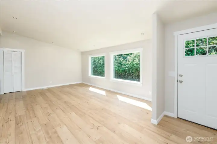 Bright additional living area with updated wood-look LVP flooring and large windows that bring in abundant natural light.
