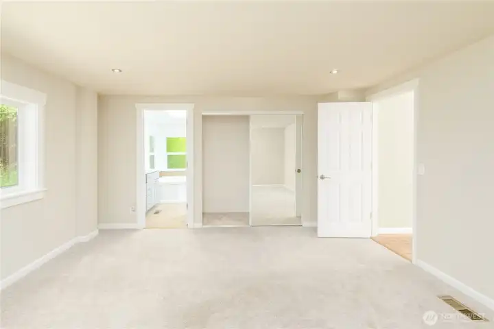 Spacious primary bedroom with an ensuite bath, mirrored closet doors, and new carpet.