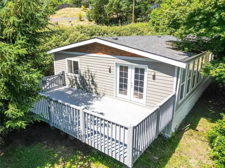 Aerial view showcasing the expansive deck, refreshed exterior, and peaceful setting surrounded by mature trees