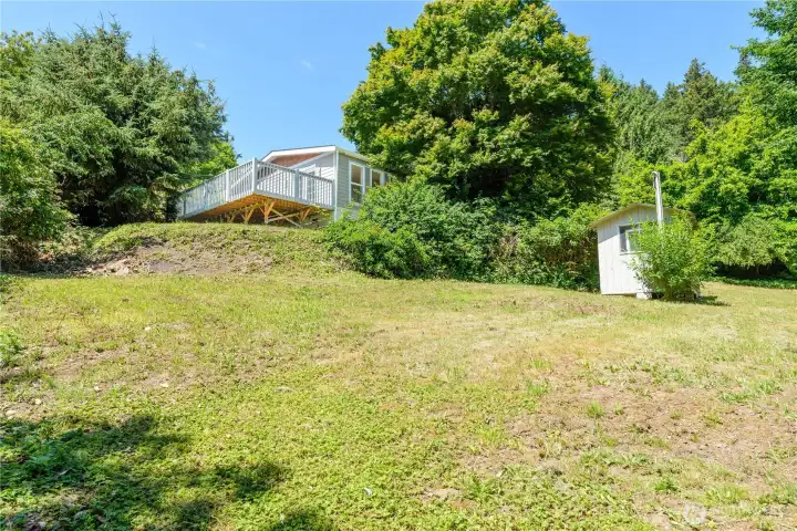 From above, the property's spacious yard, wraparound deck, mature trees, and storage shed come together to create a private outdoor setting with room to relax, garden, or play.