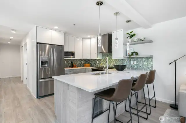 As you walk down the hallway you are greeted by the good sized and recently updated kitchen with a dedicated dining space (to the left of this photo), and open concept kitchen/dining/living room. To the left of the refrigerator and down the hallway are the two bedrooms, which would be on your left.