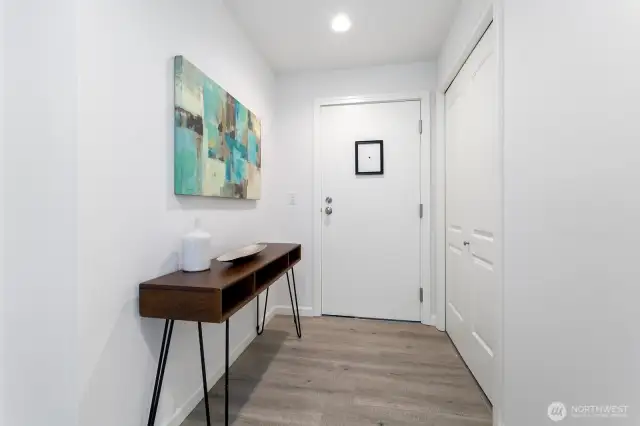 Once we step inside, you're greeted by a cute entry area. Note the updated engineered laminate flooring throughout the unit as well. In the closet on the right is your in unit washer and dryer.