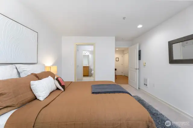 This is a great shot of the good sized primary bedroom, as we look through to the large walk-in closet and en-suite bath. Through the door on the right you'll see the front door and hallway.