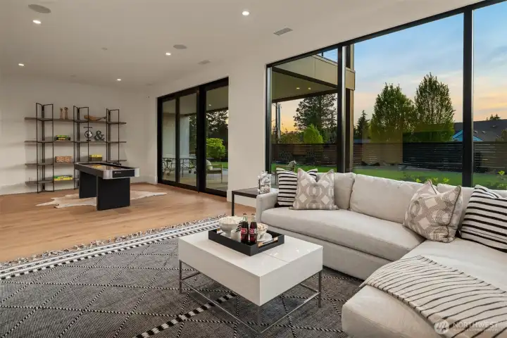 Expansive lower-level recreation room with game area, lounge seating, and seamless access to the outdoor patio.