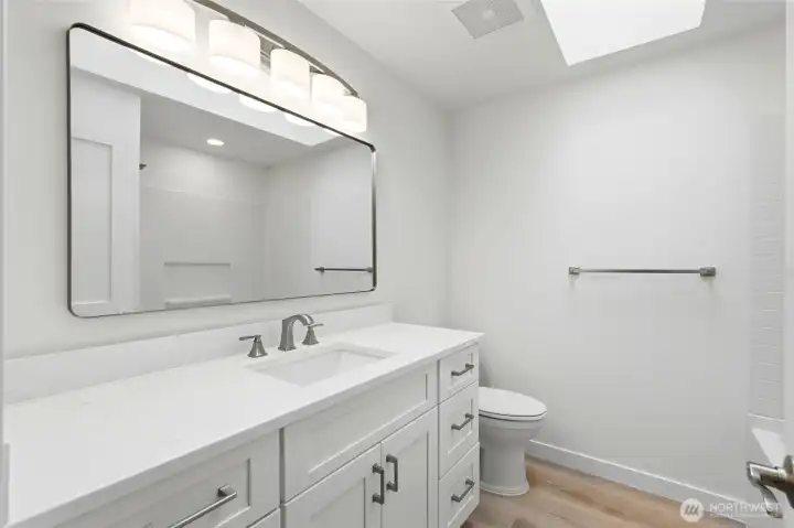 Main bathroom offers all new everything -  quartz counters, vanity with ample storage drawers, a large mirror, lighting & fixtures.