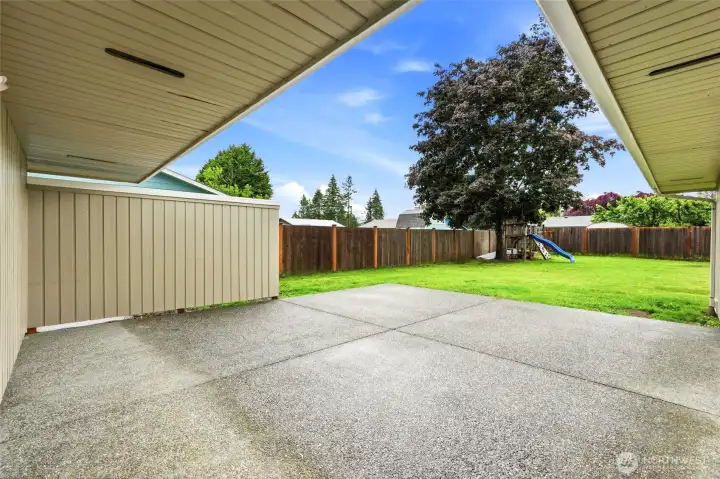 Aggregate concrete patio is partially sheltered by the deep roof overhang, offering an ideal space for outdoor dining and entertaining.