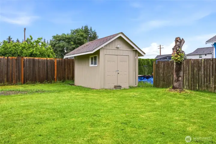 Detached storage shed features double doors for easy lawnmower entry, a dedicated window for ventilation, and matching exterior trim and siding.