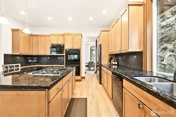 Natural wood tones pair perfectly with the green landscape surrounding the home. The kitchen offers a gas cooktop, granite countertops and abundant cabinet space. Natural wood tones pair perfectly with the green landscape surrounding the home. The kitchen offers a gas cooktop, granite countertops and abundant cabinet space.