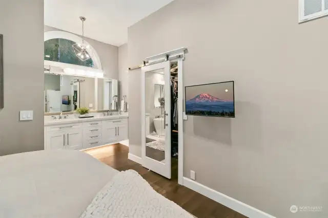 The Walk-in Closet is Complete with a Dual Sided Mirrored Door. The Dual Sink Vanity with Undermount Lighting is in View. Around the Corner is the Private Water Closet.