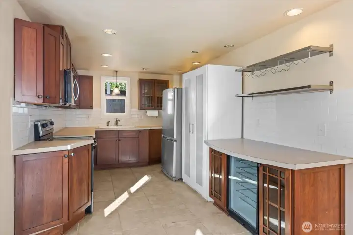 Full kitchen with wood cabinetry, tile flooring, stainless appliances, subway tile backsplash, and a wine fridge